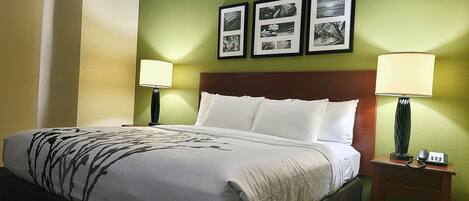 Una cama bien tendida con sábanas blancas y un plaid blanco y negro. Hay dos lámparas de noche y una mesita con un teléfono.