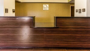 Un espace d'accueil avec un comptoir en bois, une enseigne indiquant « Sleep Inn » et une grille de ventilation fixée au mur au-dessus du comptoir.