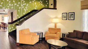 Un hall d’hôtel avec un escalier, deux canapés, une table et une lampe.