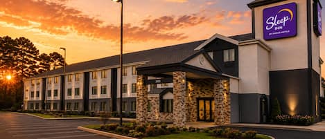 A Sleep Inn by Choice Hotels building with a parking lot and a landscaped entrance.