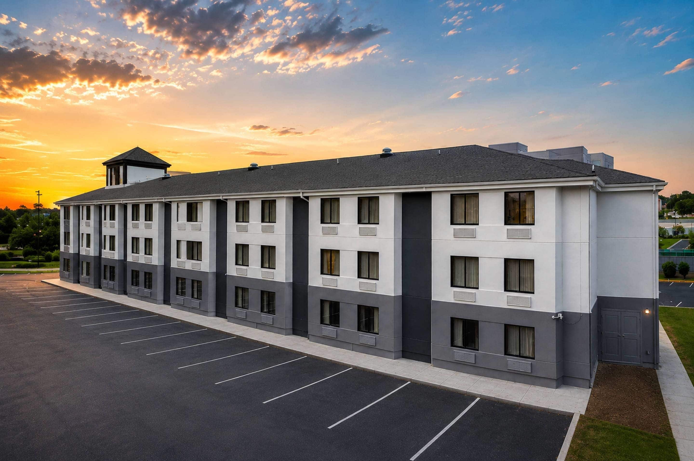 A multi-story hotel with a parking lot in front.
