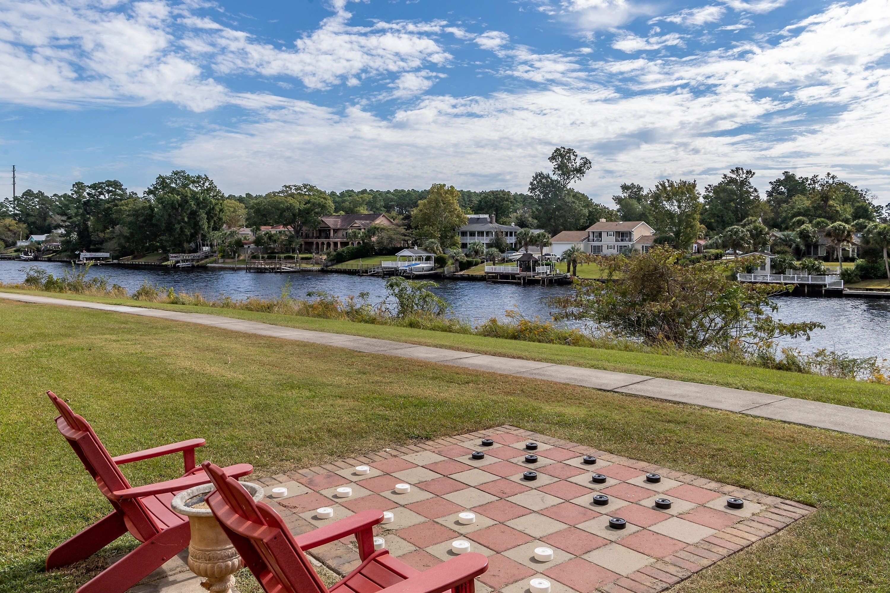 A checkered outdoor game area with a water body and houses in the background.
