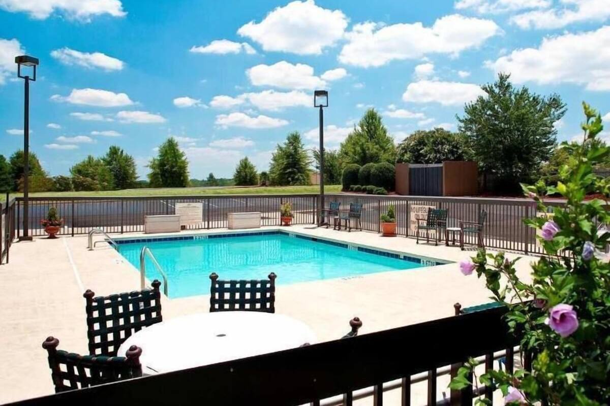 A swimming pool with a fenced deck, outdoor seating, and a clear view of the sky.