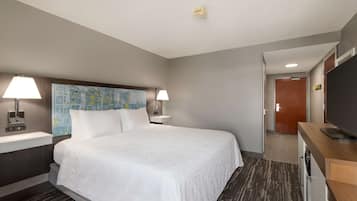 Habitación de hotel con una cama grande, dos lámparas de noche, un mapa en la cabecera, un televisor de pantalla plana, un escritorio de madera y una lavadora.