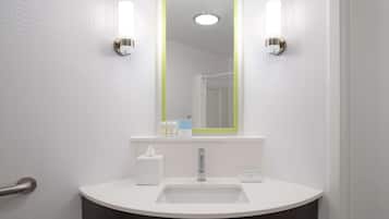 Un baño con un lavabo blanco, un espejo con marco verde y dos luces fijadas a la pared.