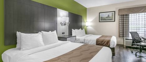 A hotel room with two beds, a desk, a chair, and a large window with curtains.