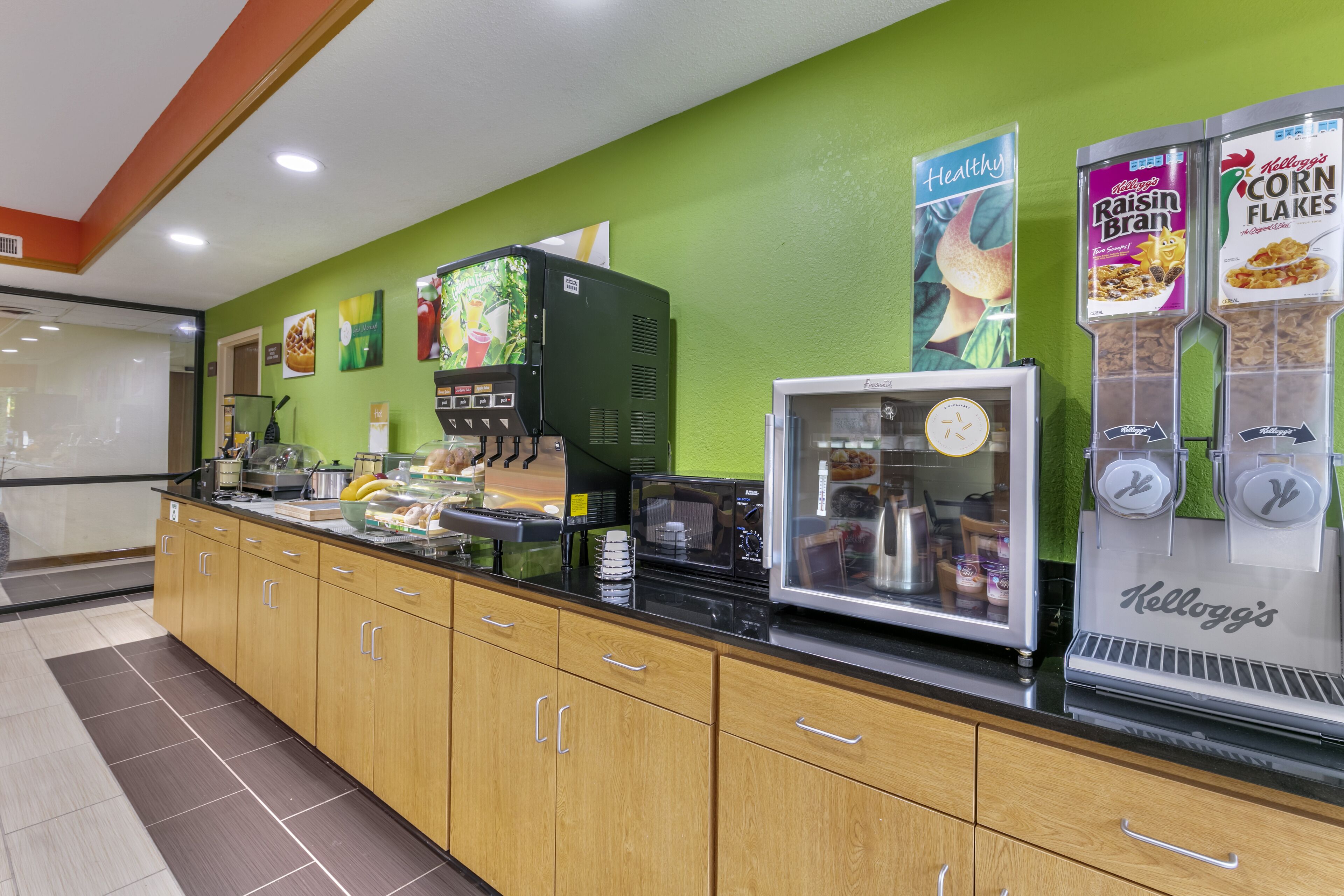 Una barra de desayuno con máquina de café, dispensadores de cereales y un refrigerador.