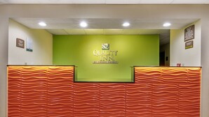 A reception desk with a green wall and a wavy orange design. - Quality Inn Rogersville (Rogersville)
