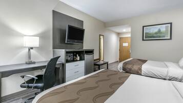 A hotel room with a bed, desk, chair, television, and a painting on the wall.