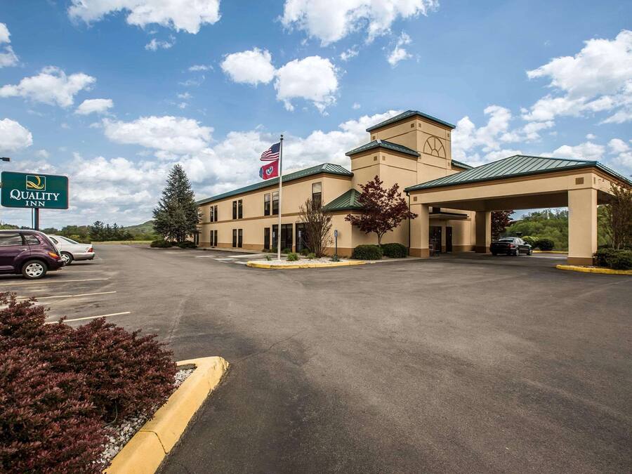 A Quality Inn with a large parking lot, a flag, and a sign.