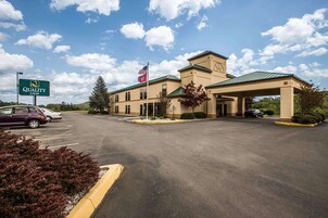 A Quality Inn with a large parking lot, a flag, and a sign.