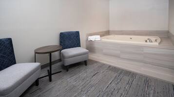 A modern bathroom with a bathtub, a small round table, and two chairs.