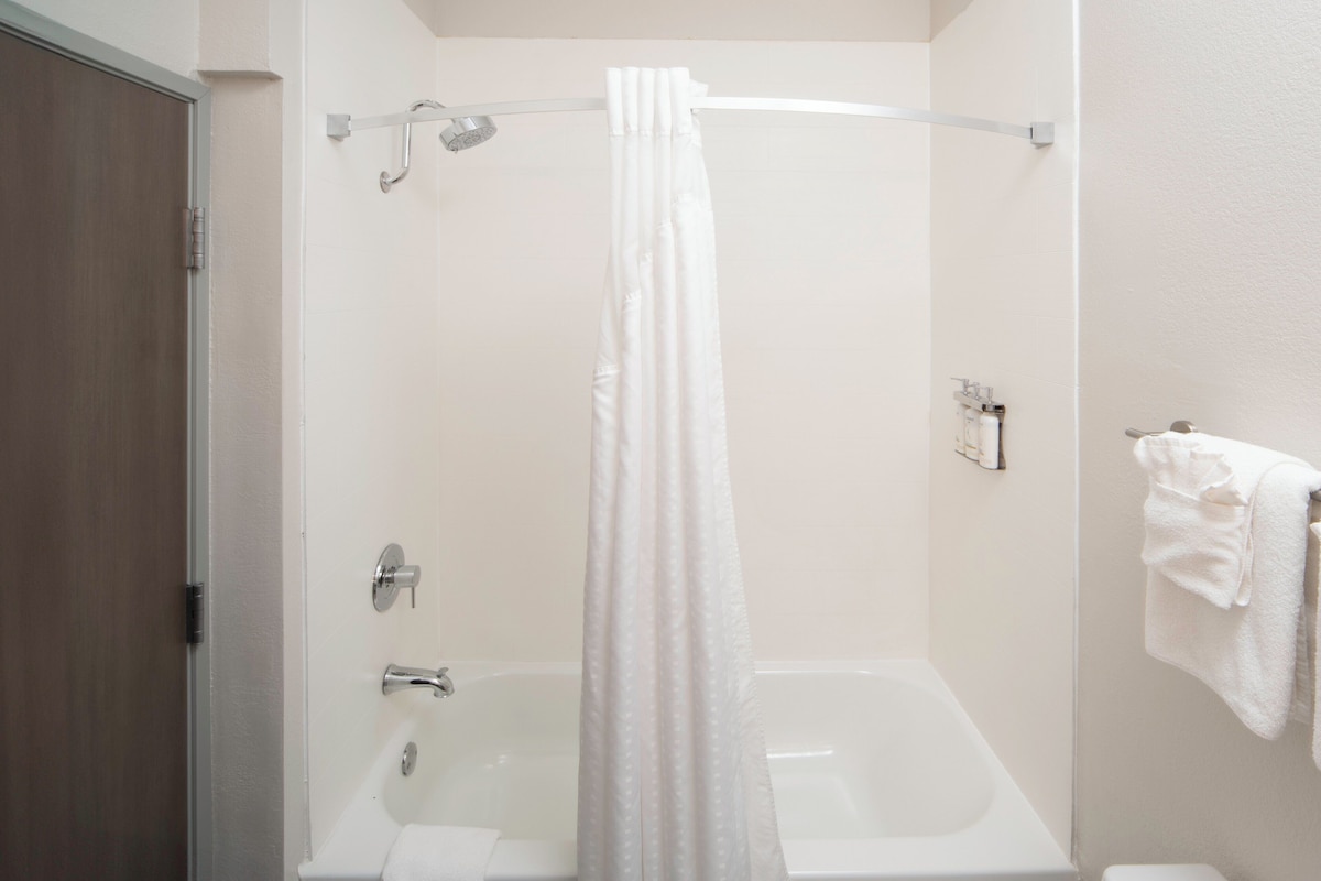 Ein Badezimmer mit einer Badewanne, einer Duschvorhang, einem Handtuchhalter und einer Toilette.