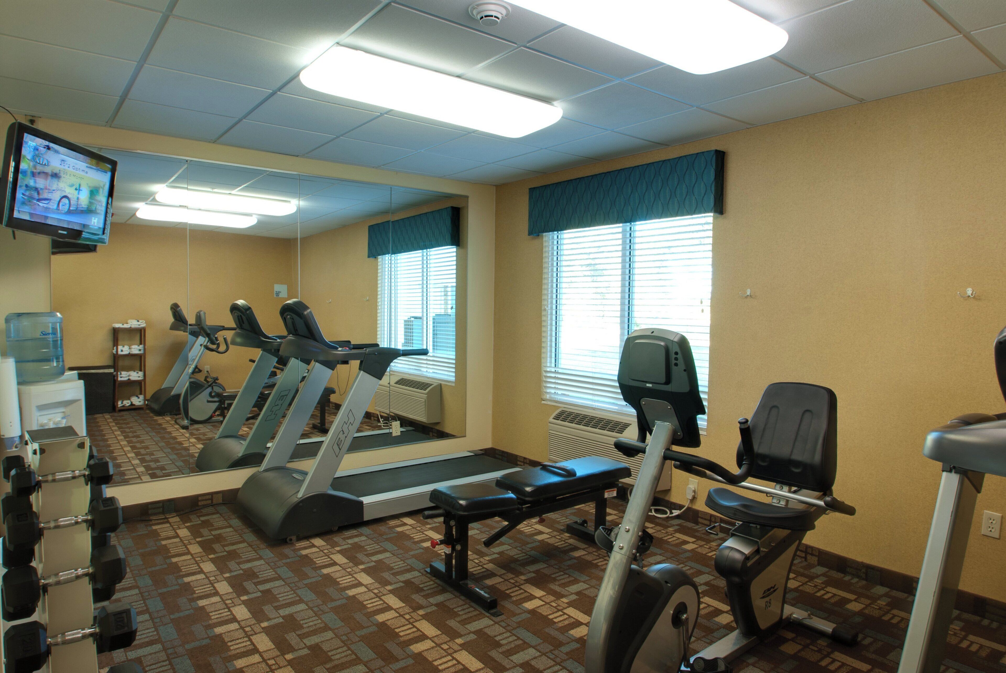 A fitness center with treadmills, elliptical machines, and free weights.