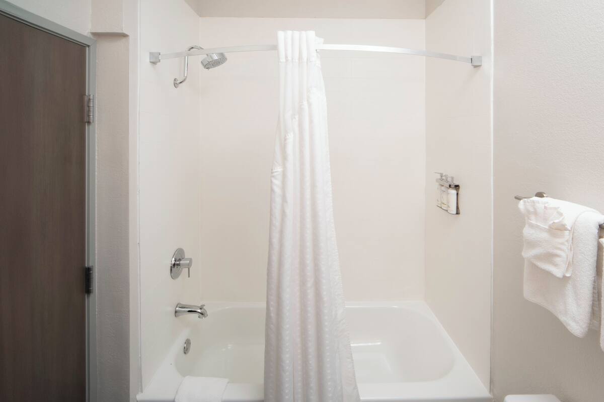A bathroom with a bathtub, a shower curtain, a towel rack, and a toilet.