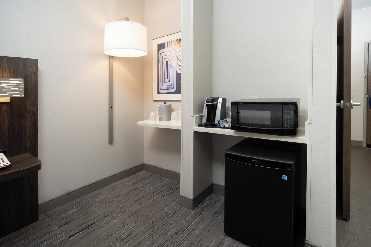 A compact kitchenette with a microwave, coffee maker, and a small refrigerator.