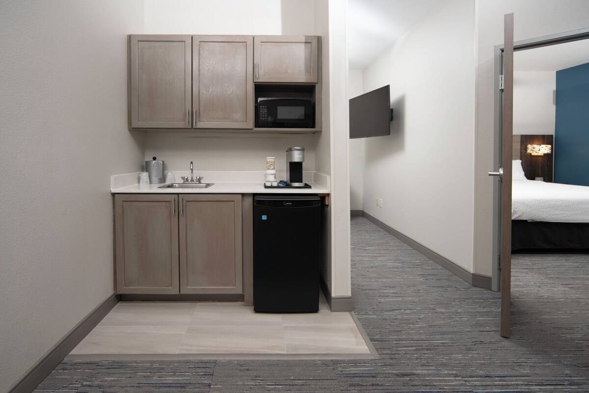 A compact kitchenette with a microwave, coffee maker, and dishwasher.