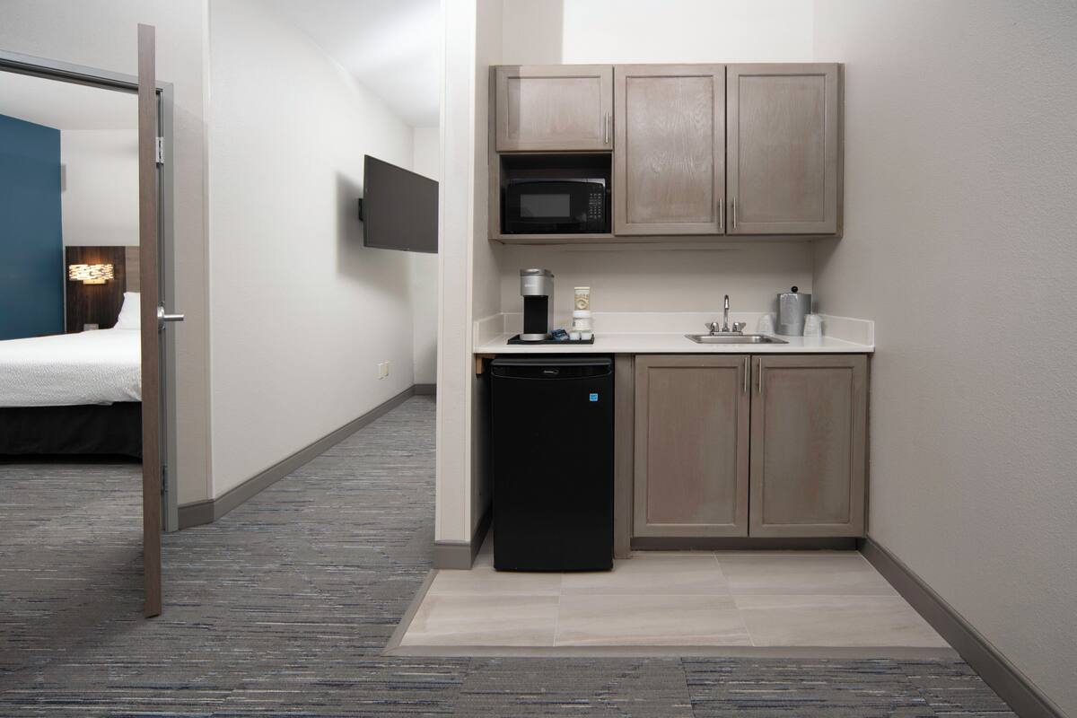 Une chambre d’hôtel compacte comprenant un coin cuisine, un lit et un téléviseur à écran plat.