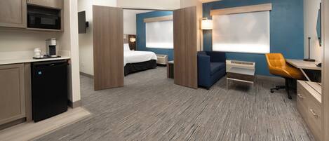 Une chambre d’hôtel équipée d’une kitchenette, d’un lit, d’un bureau et d’une chaise.
