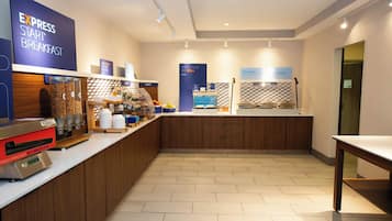 A breakfast area with a self-service station, a coffee machine, and a sign indicating breakfast is ready when the machine is full.