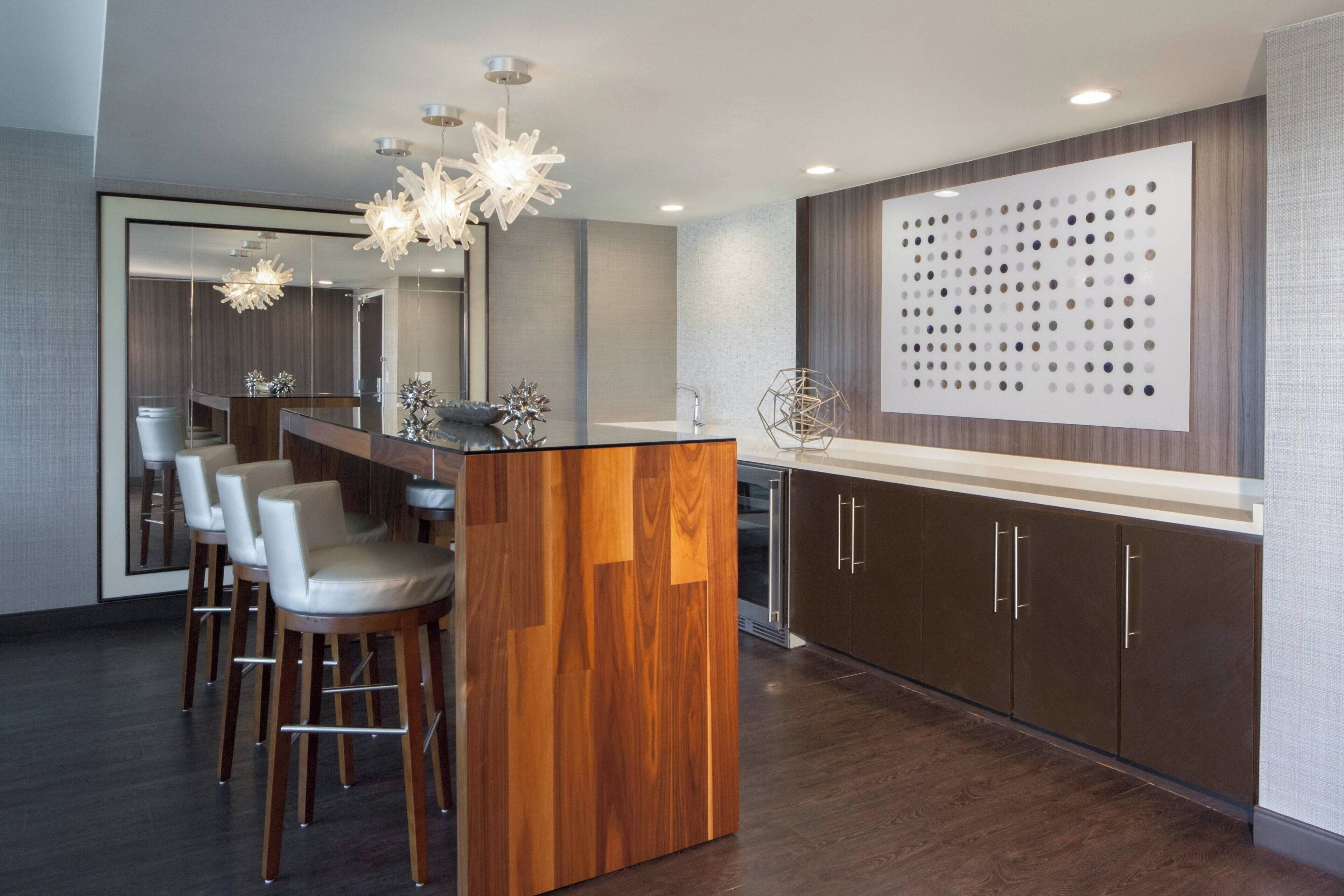 A modern kitchen with a central island, bar stools, and a decorative wall panel.