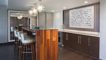 A modern kitchen with a central island, bar stools, and a decorative wall panel.