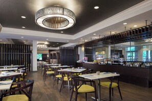 A modern restaurant interior with high tables, chairs, and a central bar area. - Dallas Marriott Suites Medical/Market Center (Dallas)