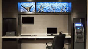 A modern office space with two monitors, a desk, a chair, and an ATM machine.