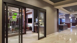 A modern hotel lobby with a glass partition, a reception desk, and a seating area with chairs and a table. - Dallas Marriott Suites Medical/Market Center (Dallas)