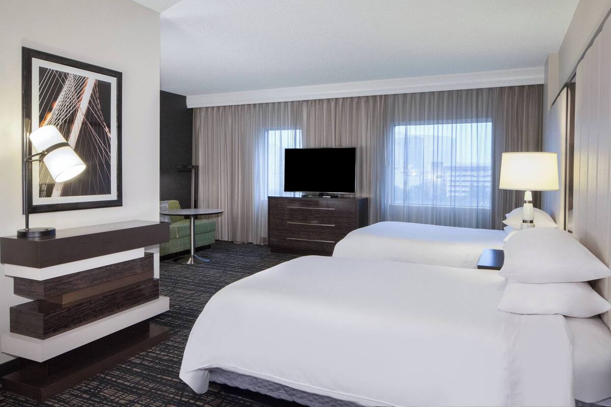 Una habitación de hotel con una cama grande, televisión, escritorio y una silla.