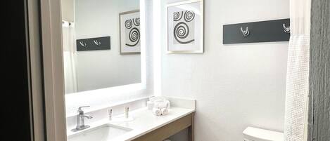 Een moderne badkamer met een grote spiegel, twee wastafels, een toilet en een douche.