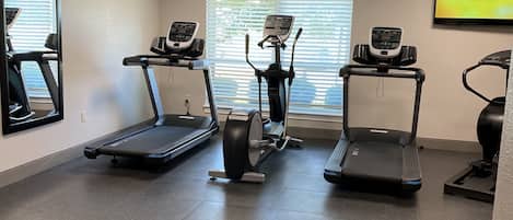 A gym with three treadmills, an elliptical, and a stationary bike.
