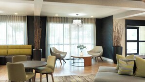 A modern hotel lobby with a sofa, round table, chairs, and a potted plant. - Courtyard by Marriott Austin Round Rock (Round Rock)