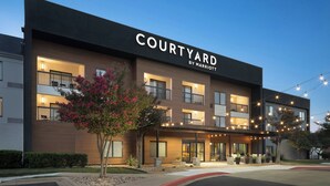A Courtyard by Marriott hotel with a modern facade, multiple balconies, and outdoor seating areas. - Courtyard by Marriott Austin Round Rock (Round Rock)