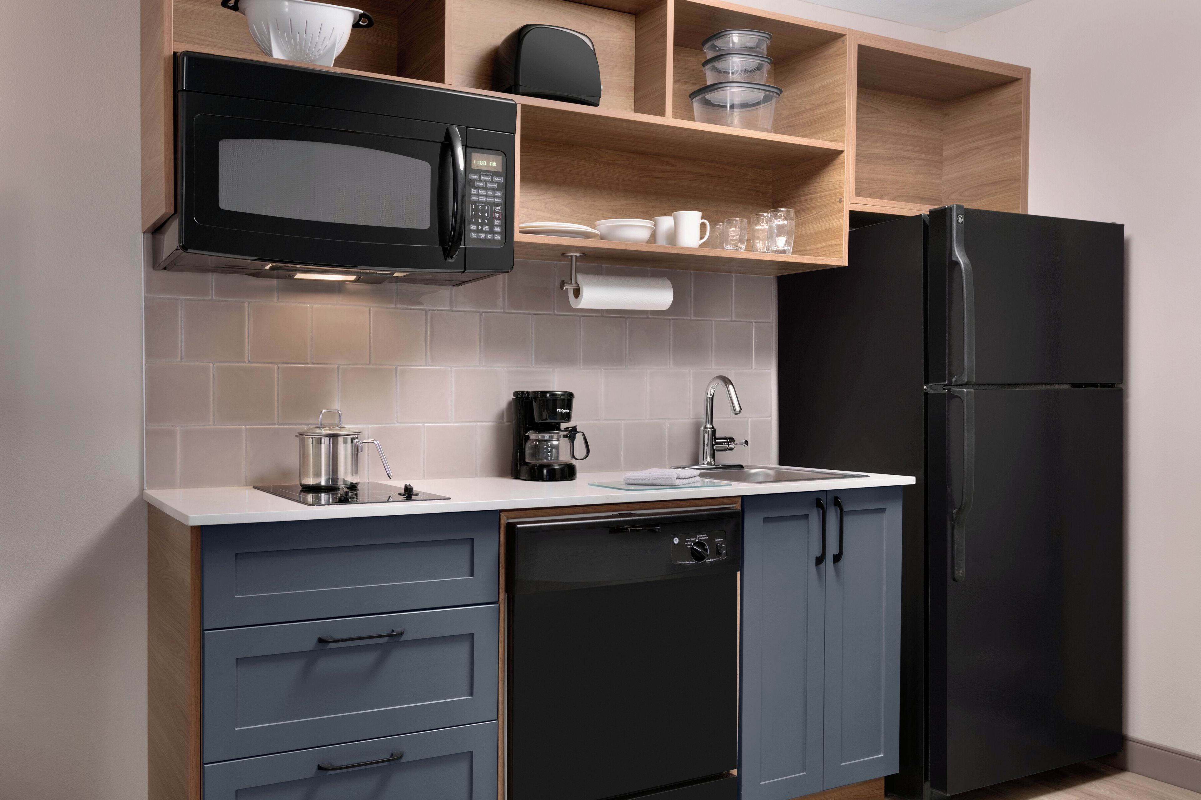 A modern kitchen with a black microwave, coffee maker, and refrigerator.