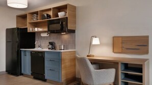 A modern kitchen with a built-in microwave, a dishwasher, and a wooden cabinet above the counter. - Candlewood Suites Houston Space Center – Webster (Webster)