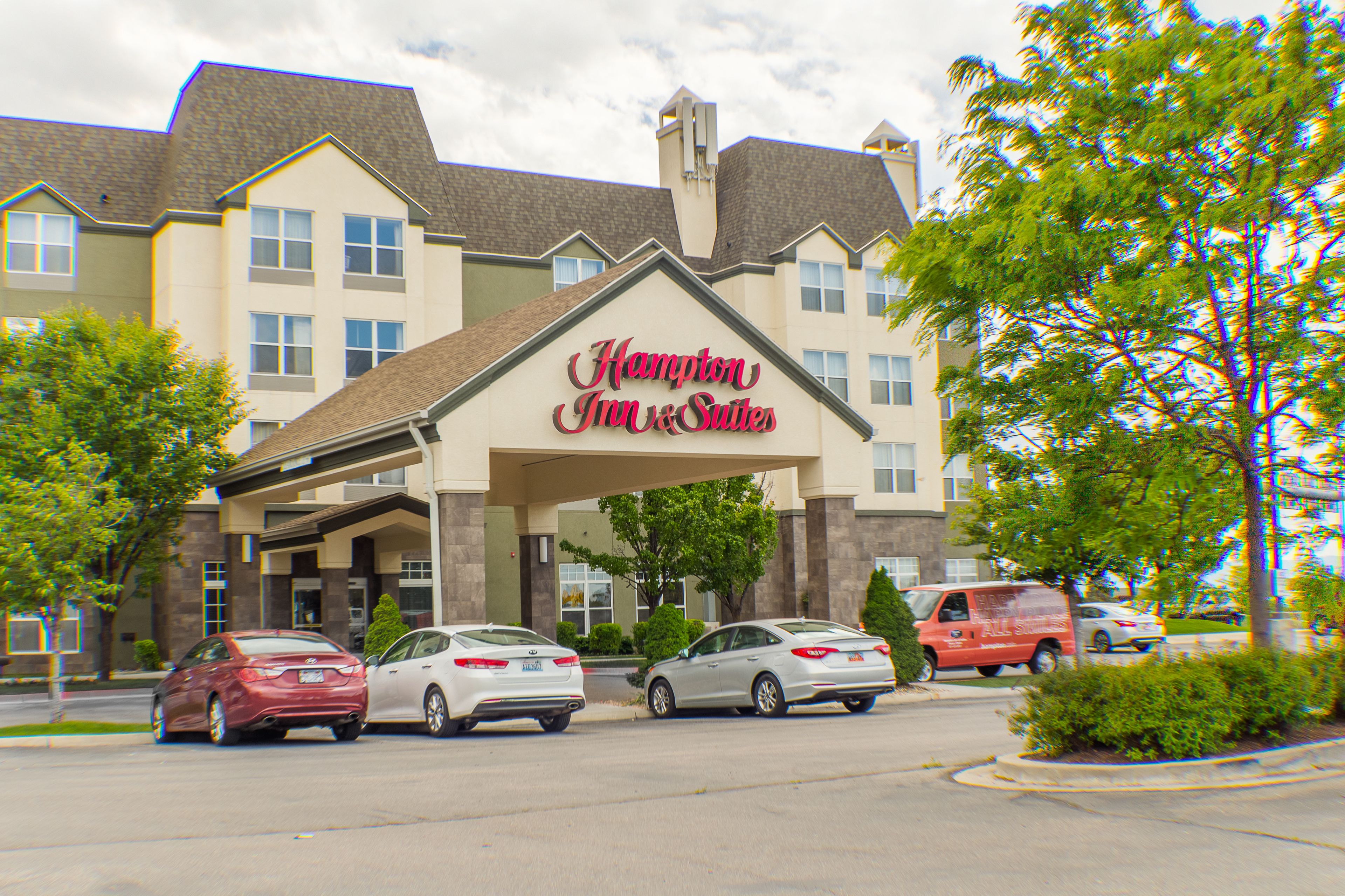 Un Hampton Inn & Suites con un estacionamiento y varios coches.