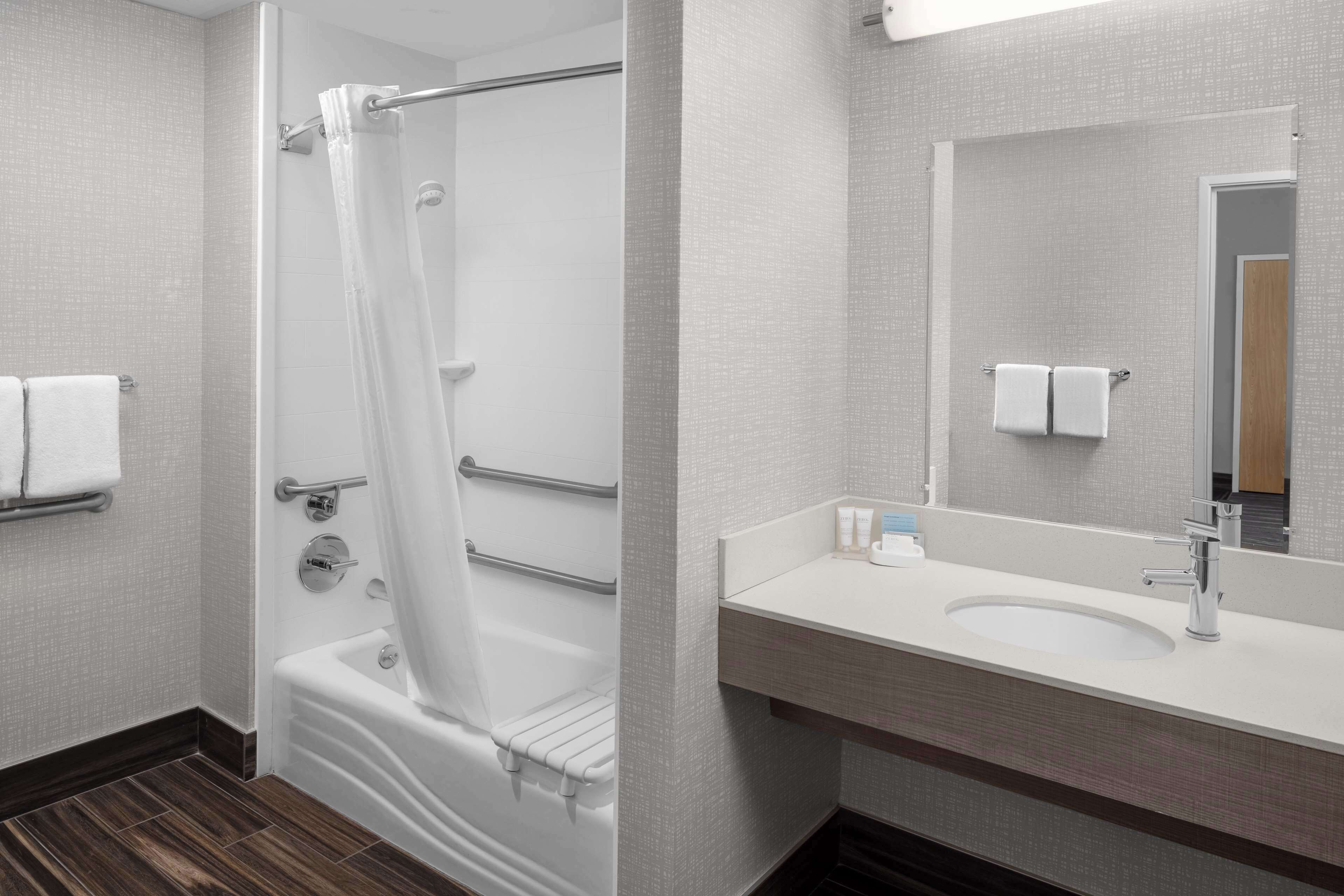 A modern bathroom with a bathtub, a shower, a sink, and a mirror.
