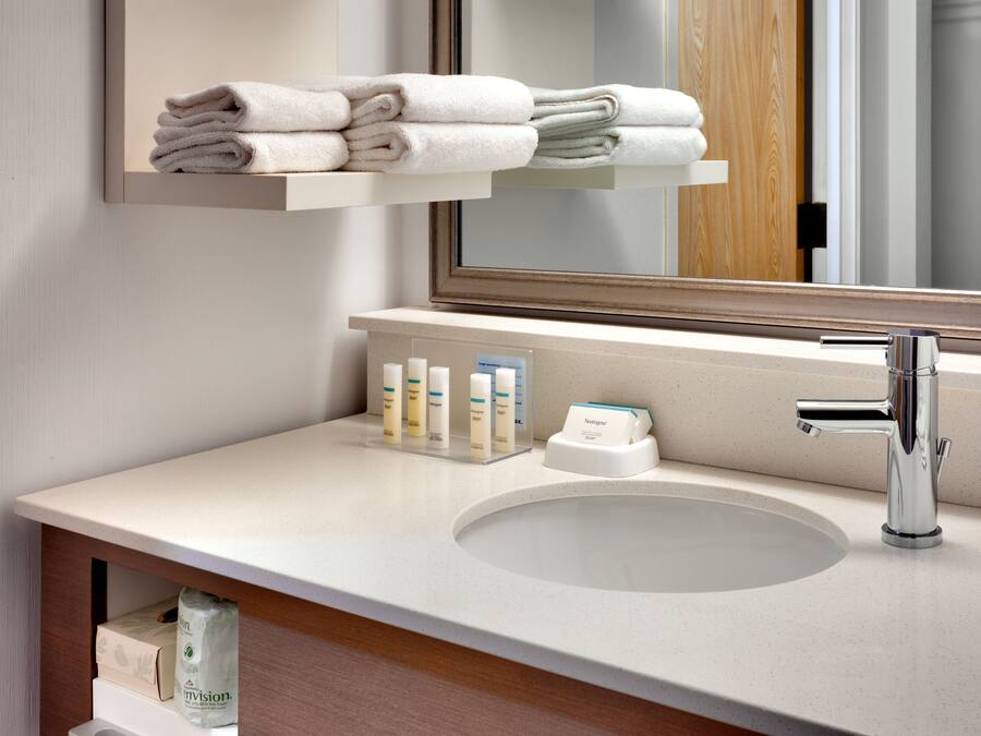 A modern bathroom with a large mirror, a sink, and a towel rack.
