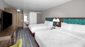 A hotel room with two beds, a TV, a desk, and a chair.