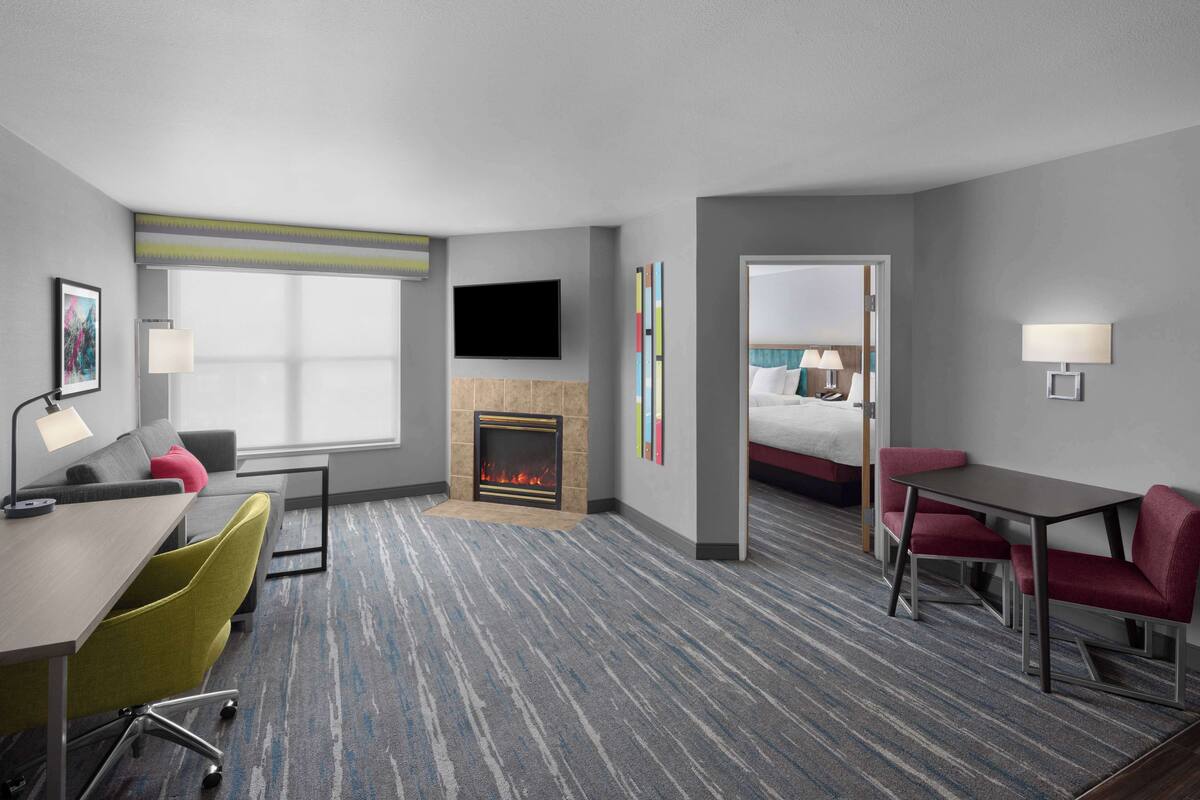 Habitación de hotel con sofá, escritorio, chimenea, televisor y cama.