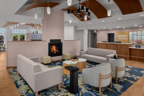 A modern hotel lobby with a fireplace, seating area, and a reception desk. - Hampton Inn & Suites Orem (Orem)