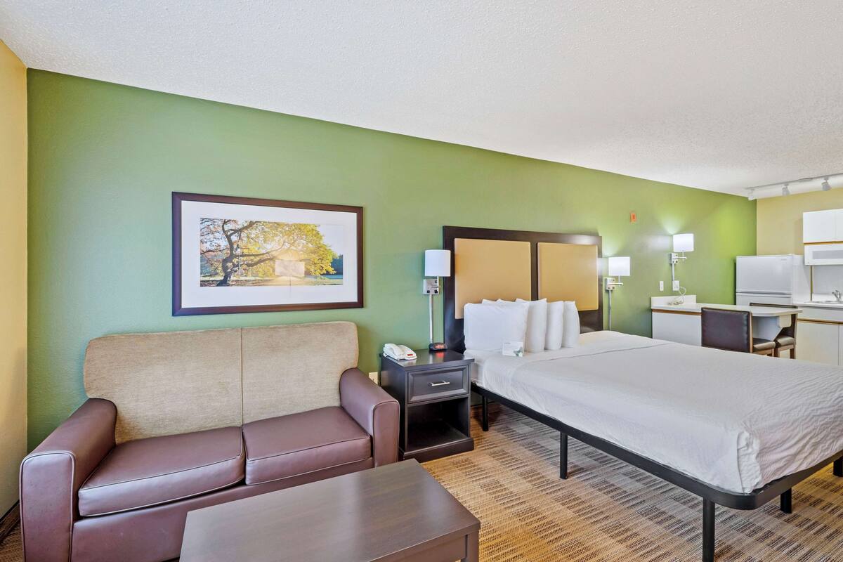 A hotel room with a bed, a sofa, a desk, and a chair.