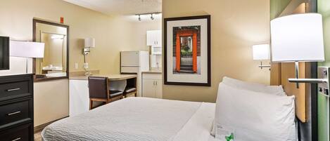 A hotel room with a bed, a desk, a chair, a telephone, and a framed picture on the wall.