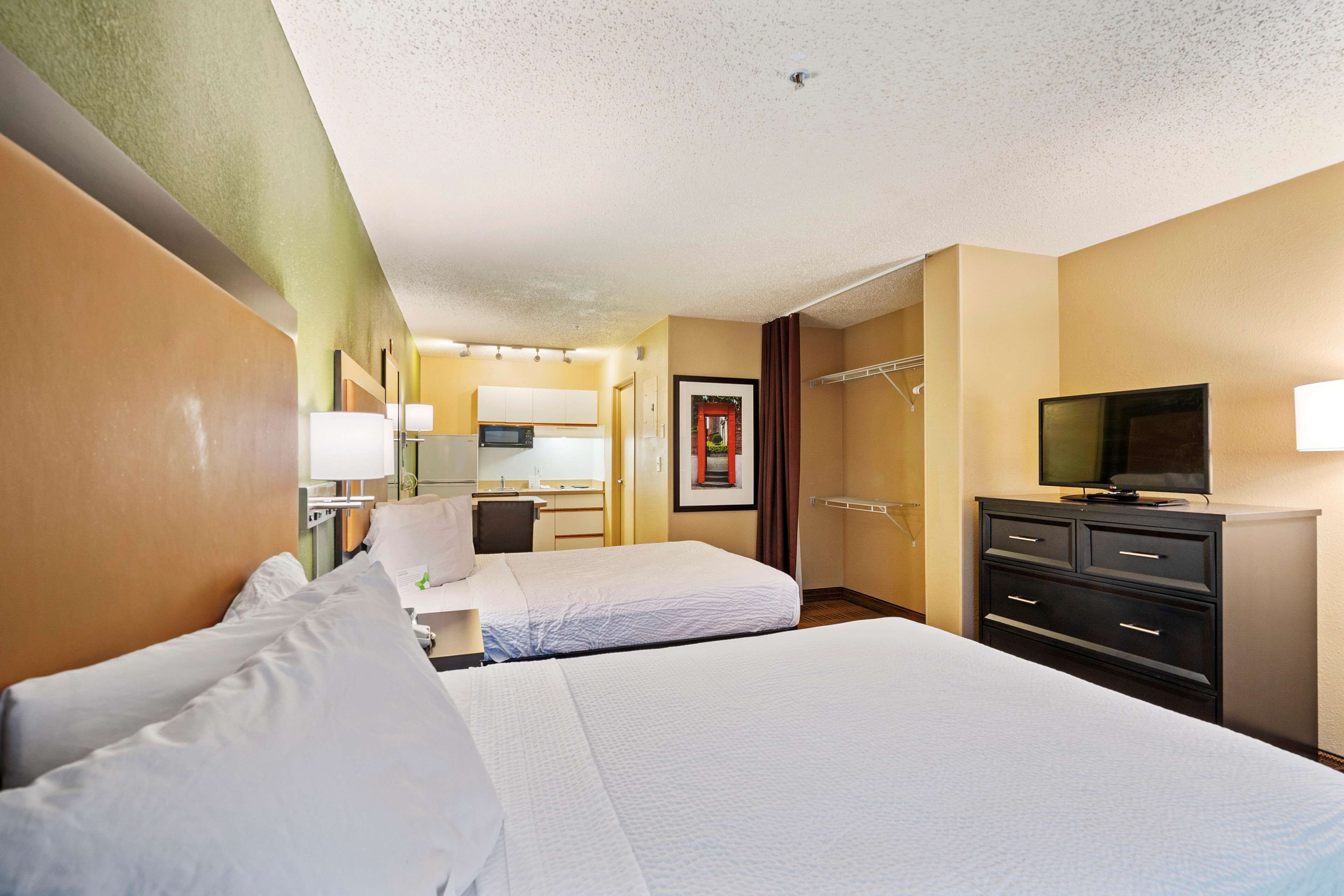 A hotel room with two beds, a desk with a chair, a television, and a wardrobe.