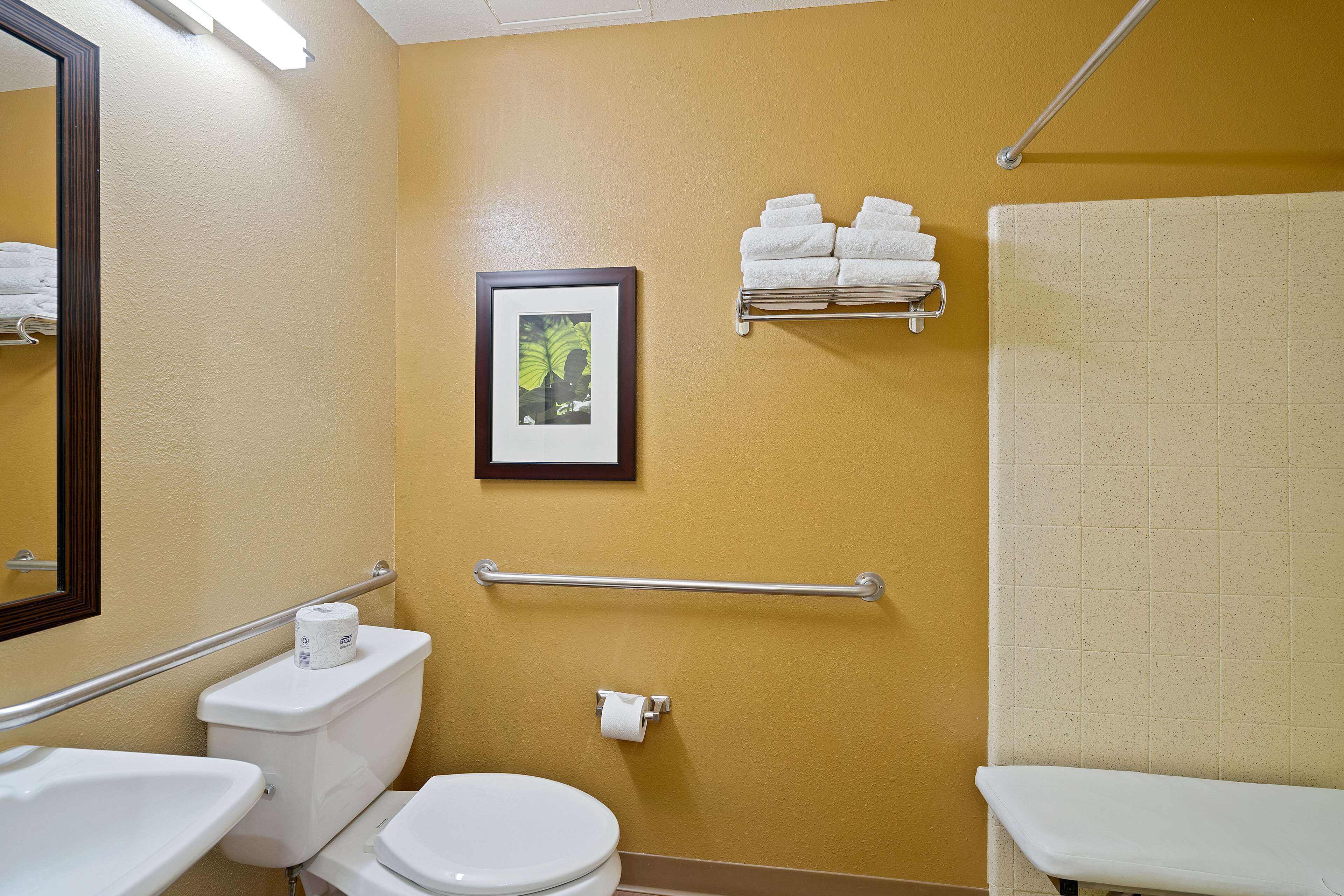 Une salle de bain comprenant des toilettes, un lavabo, un porte-serviettes et un tableau encadré au mur.