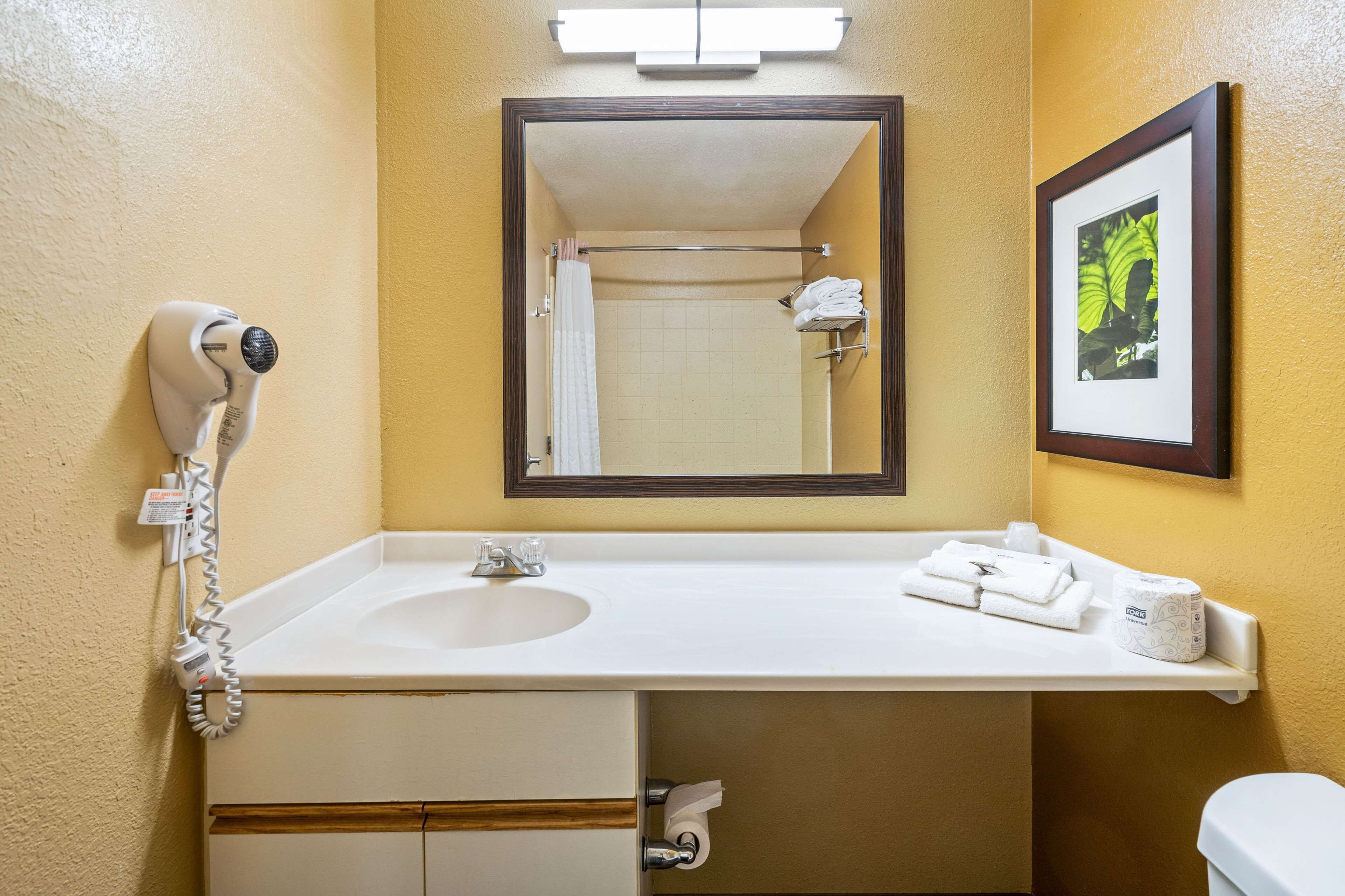 A bathroom with a white sink, a mirror, a towel rack, and a toilet.