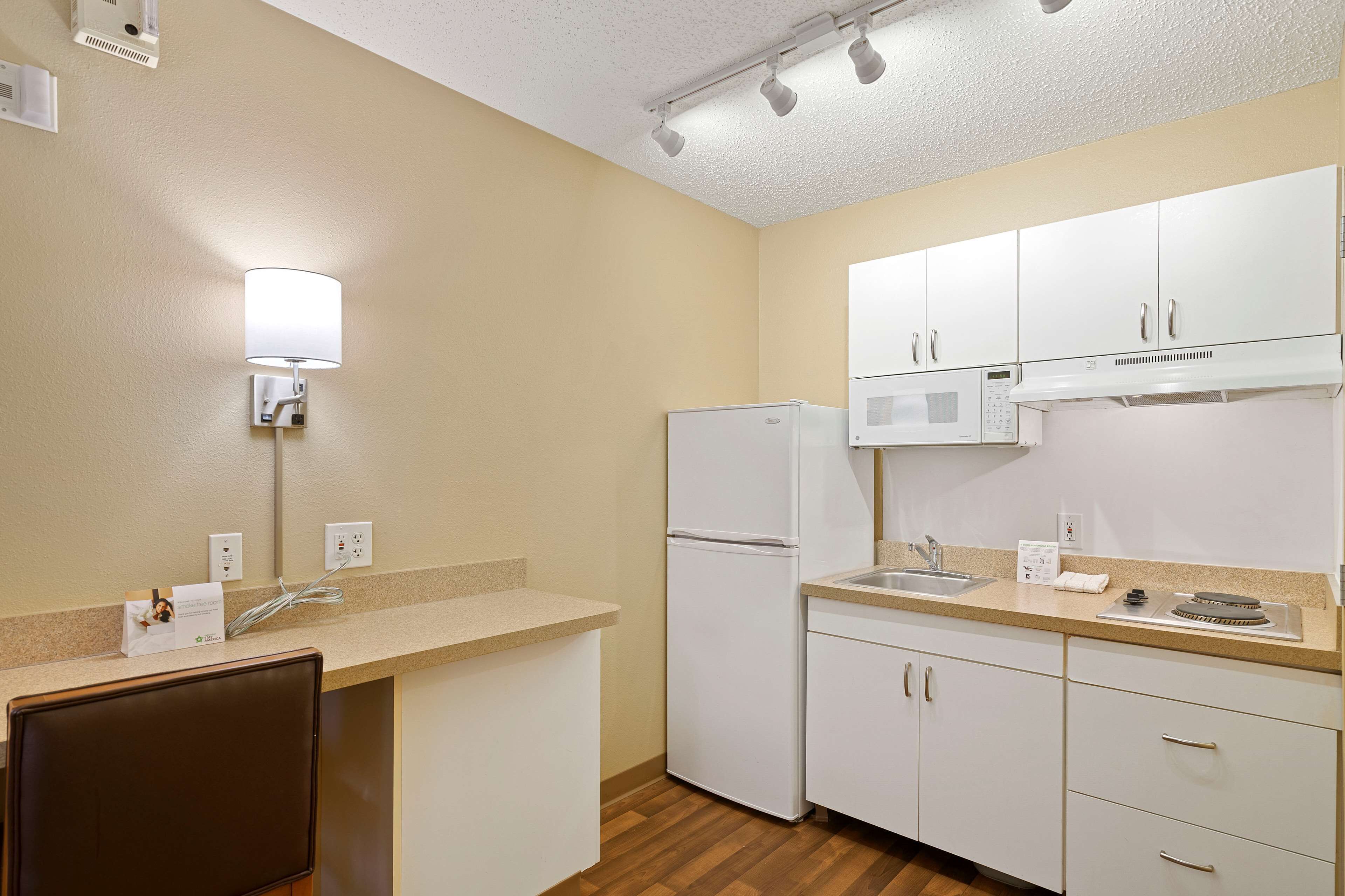 A compact kitchen with a refrigerator, microwave, and a sink.