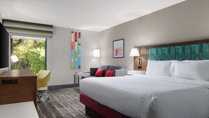 A modern hotel room with a large bed, a desk, a chair, and a window with a view of greenery. - Hampton Inn Roanoke/Hollins - I-81 (Roanoke)