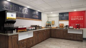 A modern kitchen area with a waffle station, a coffee machine, and various food items displayed on the counter. - Hampton Inn Roanoke/Hollins - I-81 (Roanoke)